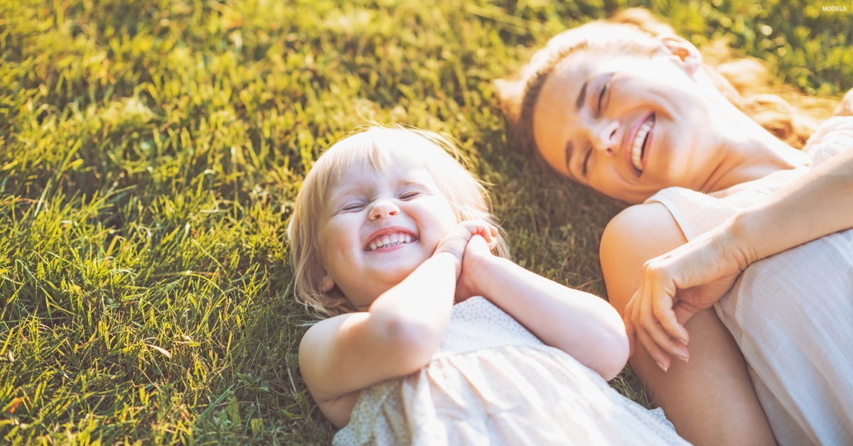 Mom and baby laughing in the grass.